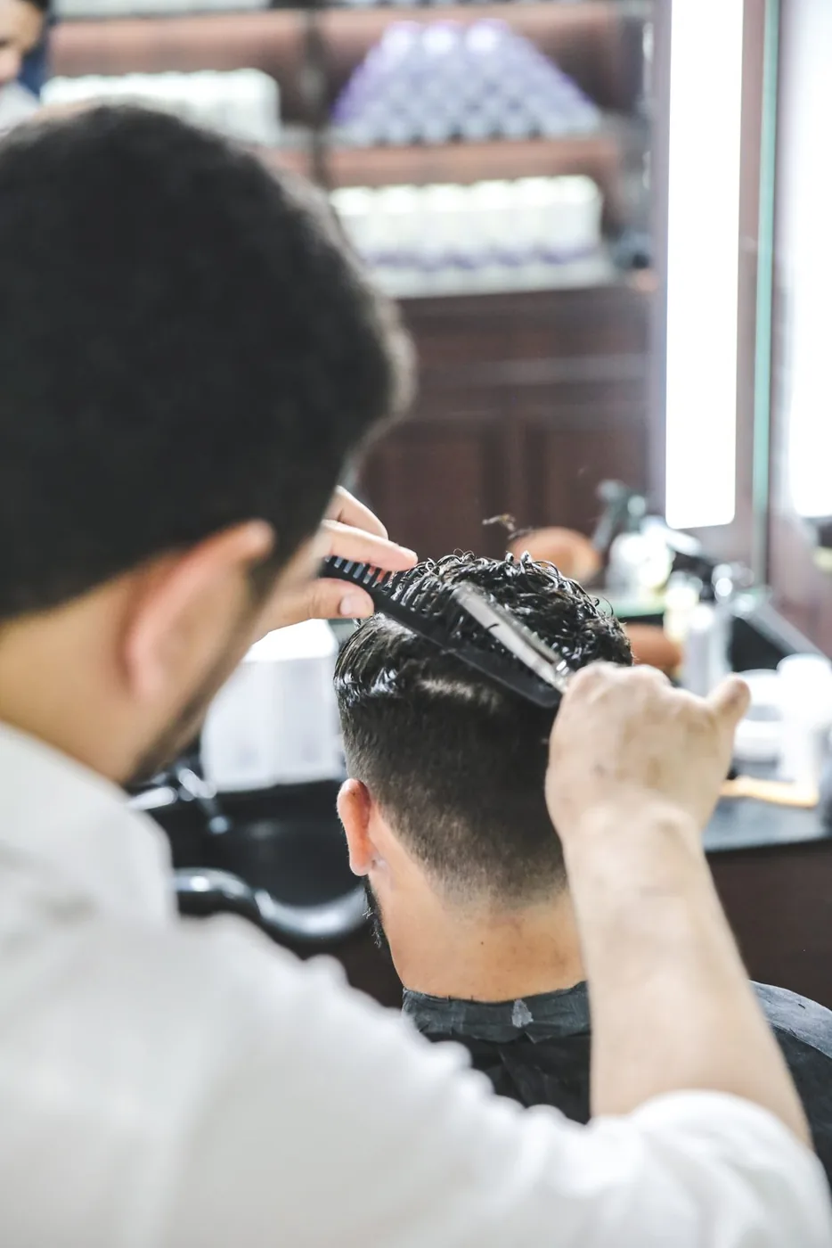 A barber combing through a classic cut at The British Barbers