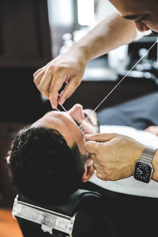 Barber providing precise facial threading service at The British Barbers premium barbershop in Chinatown Singapore – best gentleman grooming experience