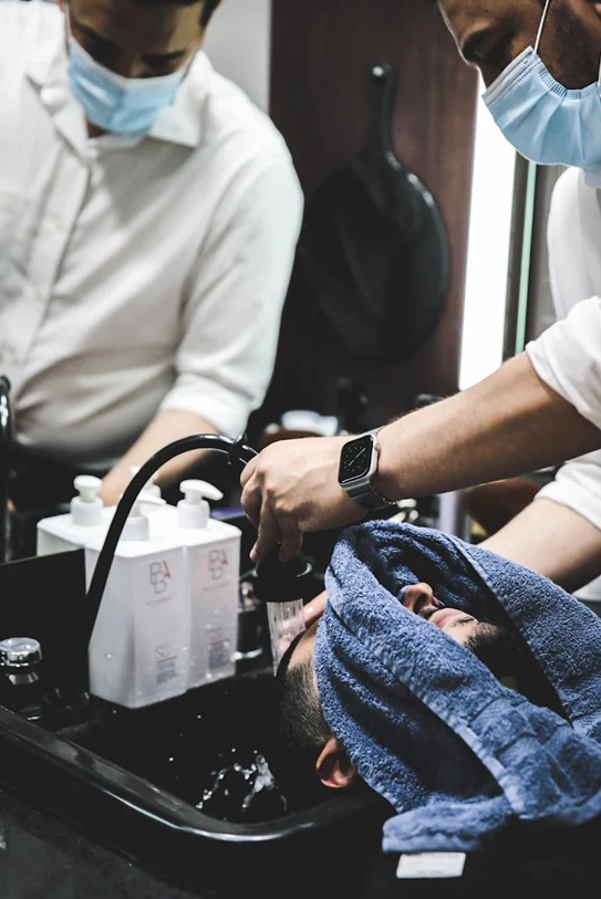 Barber washing client's hair with premium products at The British Barbers premium barbershop in Chinatown Singapore – best gentleman grooming experience