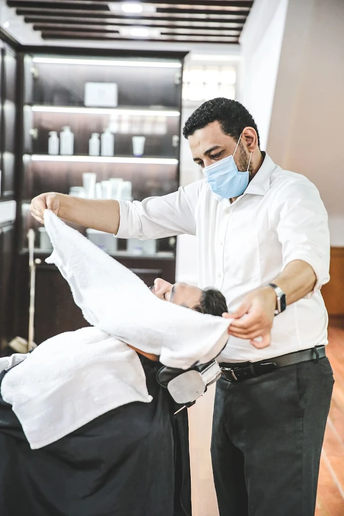 Barber applying steaming hot towel during traditional straight-razor shave at The British Barbers premium barbershop in Chinatown Singapore – best gentleman grooming experience
